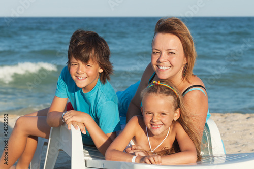Photo: Happy woman and kids relaxing on a deck chair by the sea Happy woman and kids relaxing on a deck chair by the sea