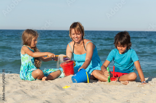 Photo: Woman and kids on the beach - playing with sand Woman and kids on the beach - playing with sand