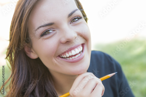 Photo: Portrait of Pretty Young Female Student with Pencil on Campus Portrait of Pretty Young Female Student with Pencil on Campus