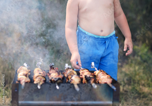 Photo: Young boy grilling kebabs on a barbecue Young boy grilling kebabs on a barbecue