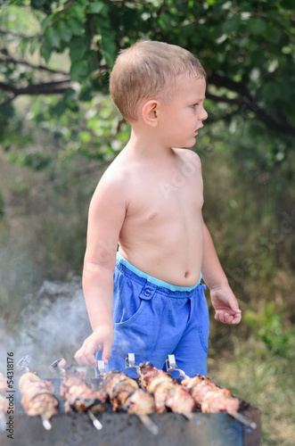Photo: Young boy grilling kebabs on a barbecue Young boy grilling kebabs on a barbecue