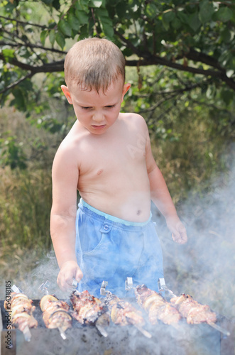 Photo: Young boy cooking at a barbecue Young boy cooking at a barbecue