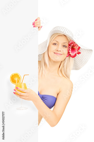 Photo: Blond woman in bikini holding a cocktail and posing behind a pan Blond woman in bikini holding a cocktail and posing behind a pan