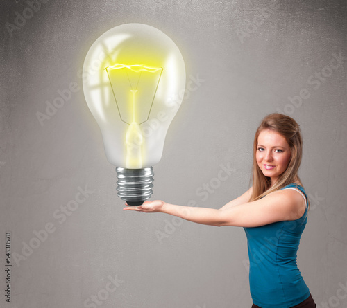 Photo: Beautiful lady holding realistic 3d light bulb Beautiful lady holding realistic 3d light bulb