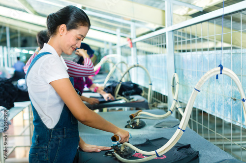 Photo: Indonesian worker with flat iron in textile factory Indonesian worker with flat iron in textile factory
