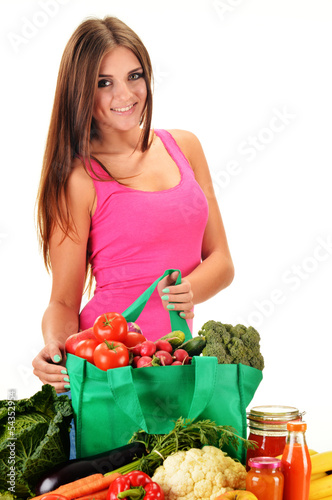 Photo: Young woman with variety of grocery products in shopping bag Young woman with variety of grocery products in shopping bag