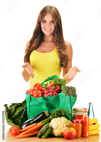 Photo: Young woman with variety of grocery products in shopping bag Young woman with variety of grocery products in shopping bag