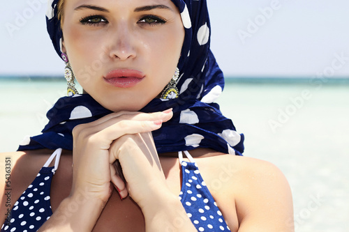 Photo: beautiful blond woman in blue shawl on beach beautiful blond woman in blue shawl on beach