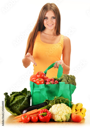 Photo: Young woman with variety of grocery products in shopping bag Young woman with variety of grocery products in shopping bag