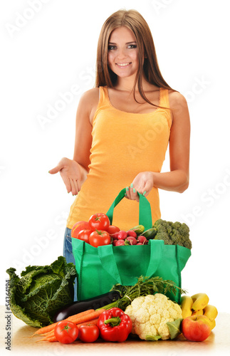 Photo: Young woman with variety of grocery products in shopping bag Young woman with variety of grocery products in shopping bag