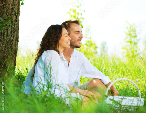 Photo: Happy Smiling Couple Relaxing in a Park. Picnic Happy Smiling Couple Relaxing in a Park. Picnic