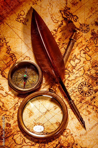 Photo: Vintage magnifying glass lies on an ancient world map Vintage magnifying glass lies on an ancient world map