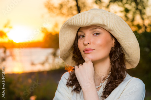 Photo: Young and beautiful woman wearing a hat in sunset light Young and beautiful woman wearing a hat in sunset light