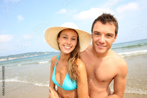 Photo: Cheerful young couple standing on the beach Cheerful young couple standing on the beach