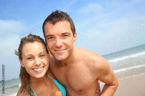 Photo: Cheerful young couple standing on the beach Cheerful young couple standing on the beach