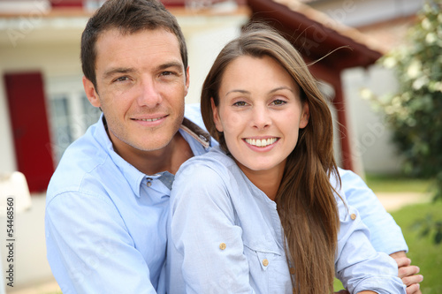 Photo: Cheerful couple standing in front of new home Cheerful couple standing in front of new home