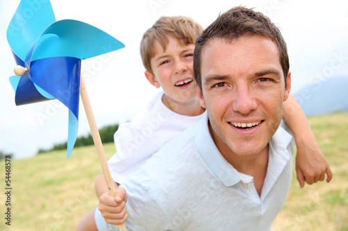 Photo: Little boy on his father's back holding windmill Little boy on his father's back holding windmill