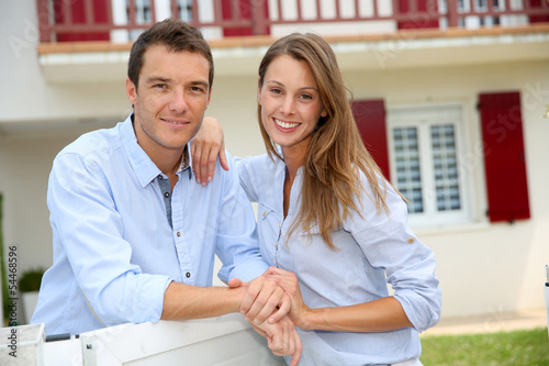 Photo: Cheerful couple standing in front of new home Cheerful couple standing in front of new home