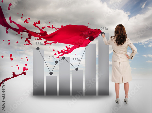 Photo: Creative businesswoman drawing a chart next to red paint splash Creative businesswoman drawing a chart next to red paint splash