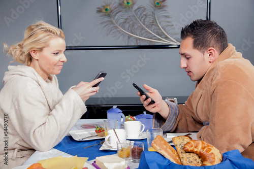Photo: Young couple in bathrobes eating breakfast Young couple in bathrobes eating breakfast