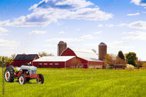 Photo: Traditional american red farm with tractor Traditional american red farm with tractor