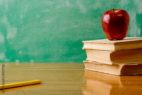 Photo: Stack of books with apple and pencil . Isolated on green Stack of books with apple and pencil . Isolated on green