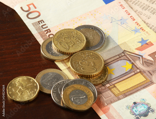 Photo: Money: euro coins and bills close up isolated on wood background Money: euro coins and bills close up isolated on wood background