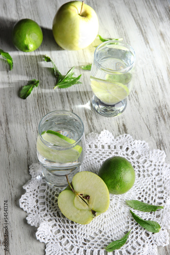 Photo: Glasses of cocktail with lime on napkin on light wooden table Glasses of cocktail with lime on napkin on light wooden table