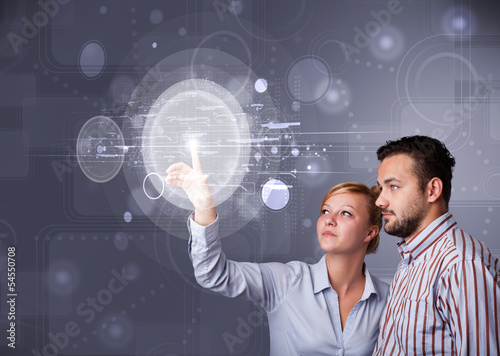 Photo: Happy couple touching abstract high technology circular buttons Happy couple touching abstract high technology circular buttons