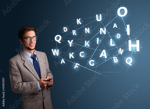 Photo: Young man typing on smartphone with high tech 3d letters comming Young man typing on smartphone with high tech 3d letters comming