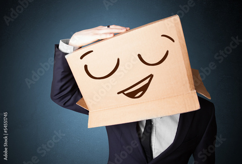 Photo: Businessman gesturing with a cardboard box on his head with smil Businessman gesturing with a cardboard box on his head with smil