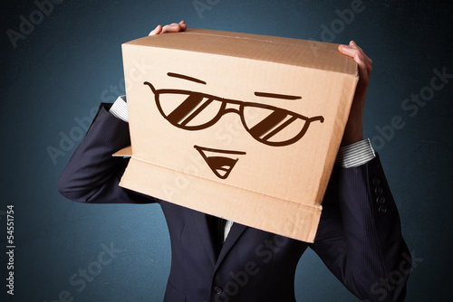 Photo: Businessman gesturing with a cardboard box on his head with smil Businessman gesturing with a cardboard box on his head with smil