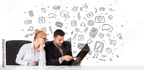 Photo: Businessman and businesswoman with all kind of hand-drawn icons Businessman and businesswoman with all kind of hand-drawn icons