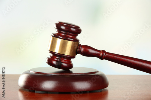 Photo: Judges gavel on wooden table on light background Judges gavel on wooden table on light background