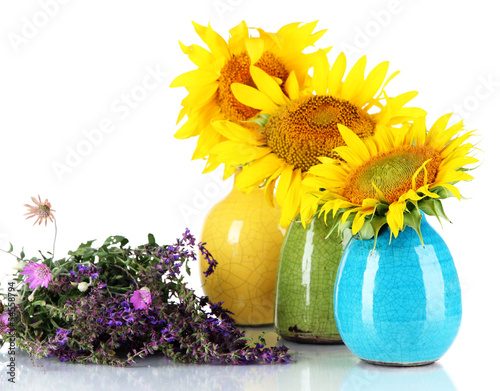 Photo: Beautiful sunflowers in color vases and wild flowers, isolated Beautiful sunflowers in color vases and wild flowers, isolated