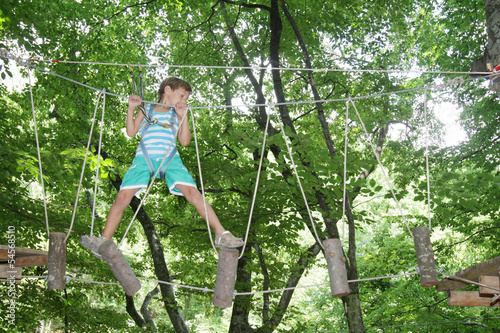 Photo: young happy child boy in adventure park in safety equipment young happy child boy in adventure park in safety equipment