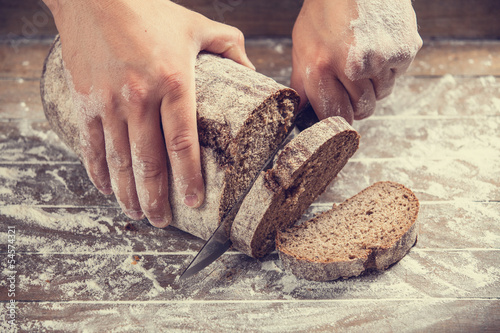 Photo: Male hands slicing home-made bread Male hands slicing home-made bread