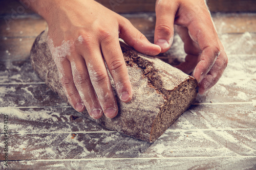 Photo: Baker's hands with a bread. Photo with high contrast Baker's hands with a bread. Photo with high contrast