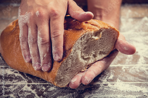 Photo: Baker's hands with a bread. Photo with high contrast Baker's hands with a bread. Photo with high contrast