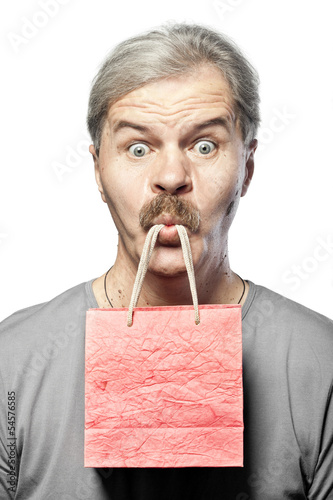Photo: surprised mature man with shopping bag in mouth isolated on whit surprised mature man with shopping bag in mouth isolated on whit