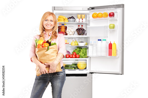 Photo: Smiling mature woman holding a bag full of groceries in front of Smiling mature woman holding a bag full of groceries in front of