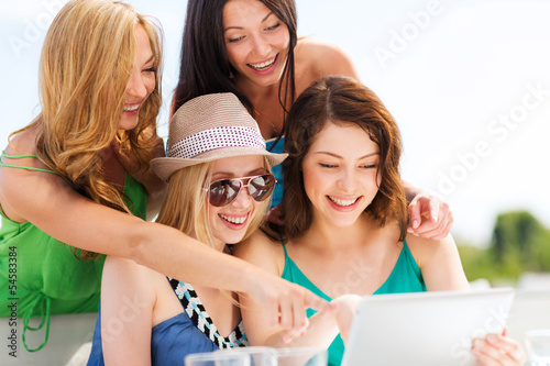 Photo: girls looking at tablet pc in cafe girls looking at tablet pc in cafe