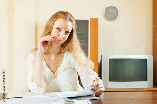 Photo: blonde woman looking financial documents at table blonde woman looking financial documents at table