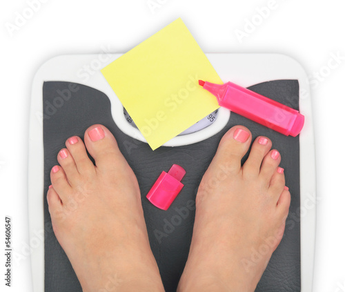 Photo: Woman' s feet on bathroom scale and blank notepaper Woman' s feet on bathroom scale and blank notepaper