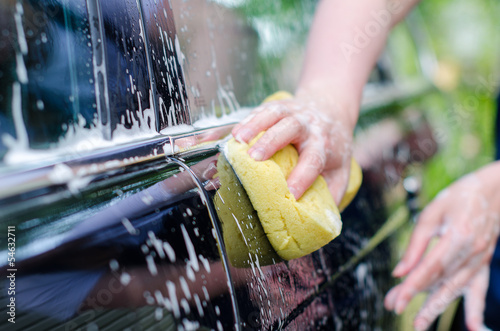 Photo: Female hand with yellow sponge washing car Female hand with yellow sponge washing car