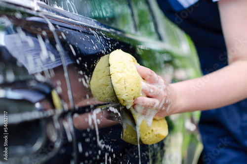 Photo: Female hand with yellow sponge washing car Female hand with yellow sponge washing car