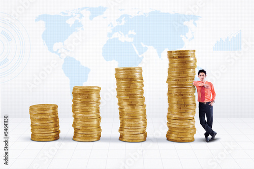Photo: Businessman and gold coins growth on world map Businessman and gold coins growth on world map