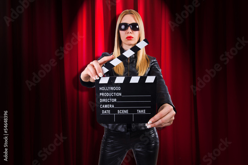 Photo: Girl with movie board against curtains Girl with movie board against curtains