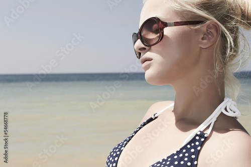 Photo: Beautiful blond woman on the beach in sunglasses Beautiful blond woman on the beach in sunglasses