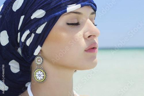 Photo: beautiful woman in a blue shawl on the beach. arabic style beautiful woman in a blue shawl on the beach. arabic style